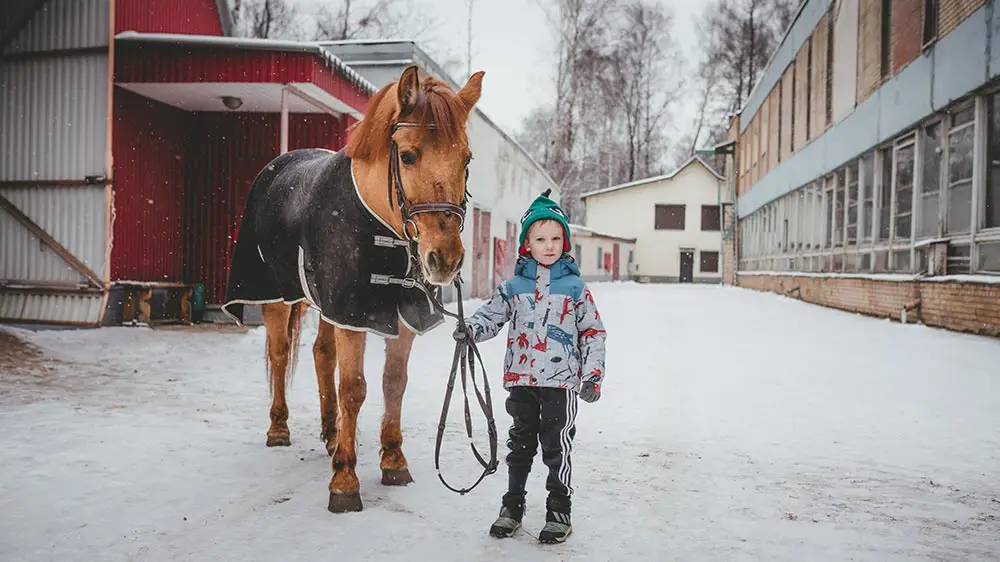 Cheval avec une couverture tenu par un enfant